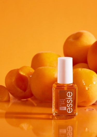 Essie cuticle oil in a classic bottle format and rollerball format with apricots in the background